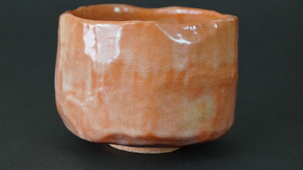 Chawan tea bowl made of Raku ware by Ichiraku Nishimura in full view with glossy orange glaze