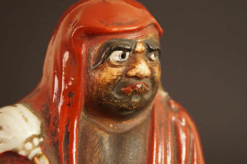 Bodhidharma Daruma figure made of red Kutani porcelain extreme close-up of the alert face face close-up