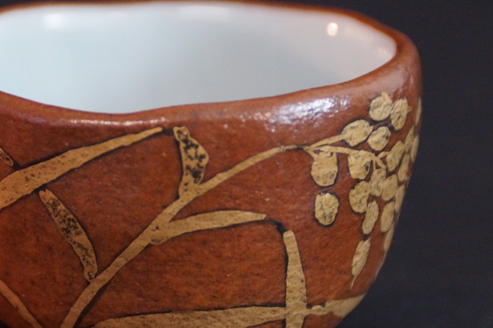 Close-up of the gold-colored branch and leaf motif on the rim of the bowl