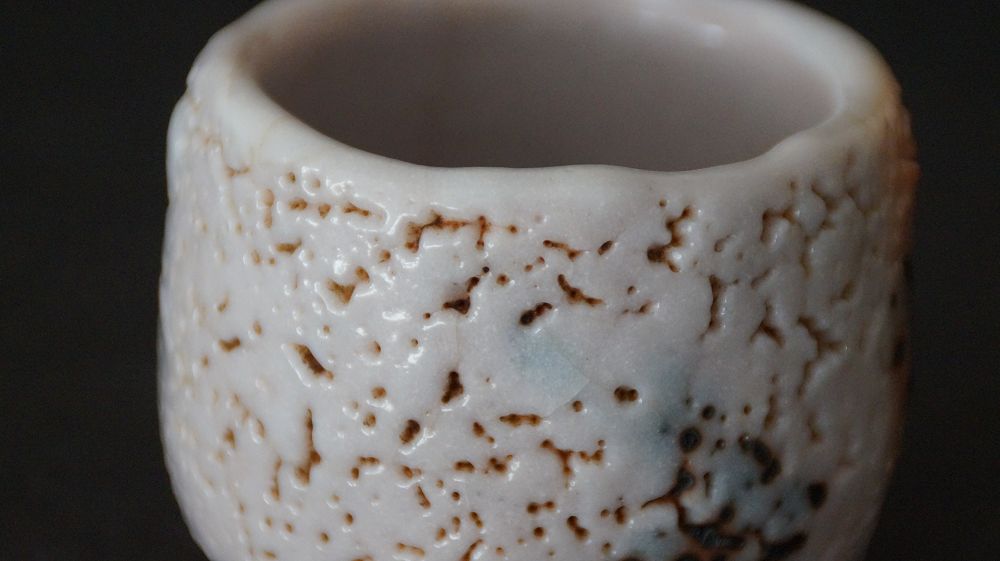 Close-up of the irregular rim with crackled glaze of the guinomi made of Shino ware by Takeshi Kato