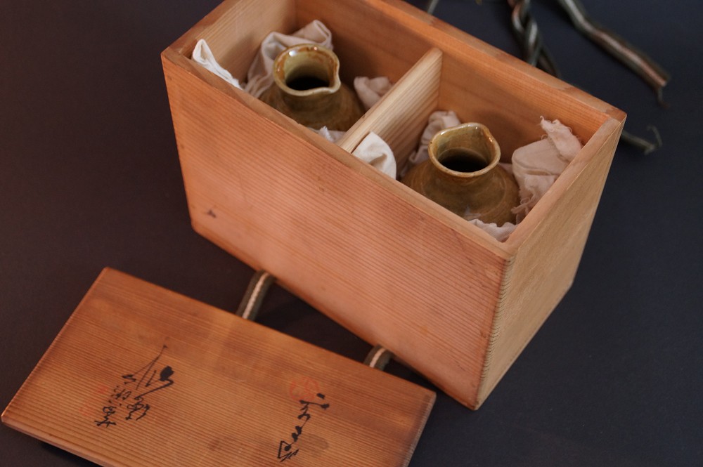 Both sake bottles nestled in the compartments of the storage box