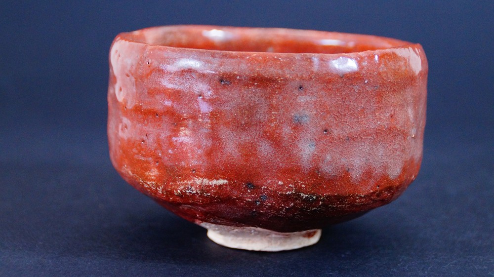 Further side view of the chawan made of Raku ware by Sairi Hotoku with dark spots in the glaze