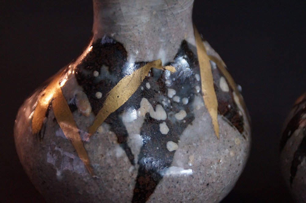 Extreme close-up of the gold-colored brushstrokes on dark speckled glaze