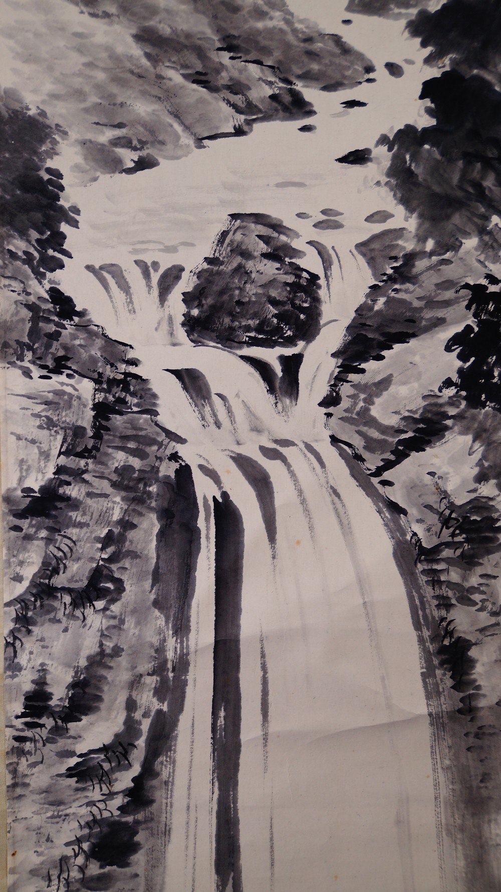 Nahaufnahme des Wasserfalls mit grossem Felsblock und Kiefern in der Tuschelandschaft
