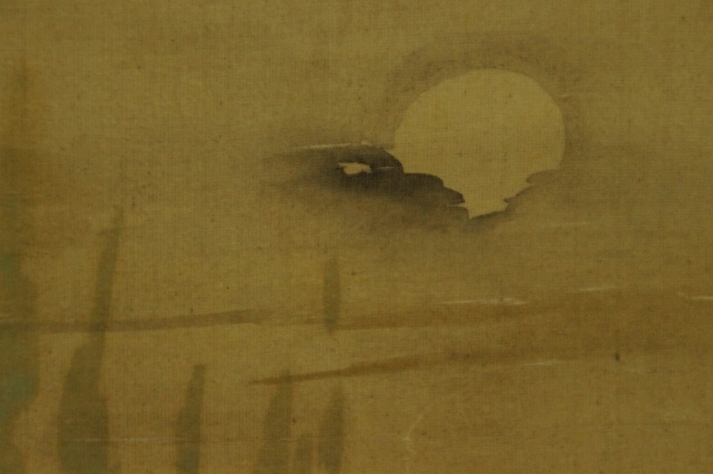 Close-up of the pale moon above the reed stalks at the edge of the image