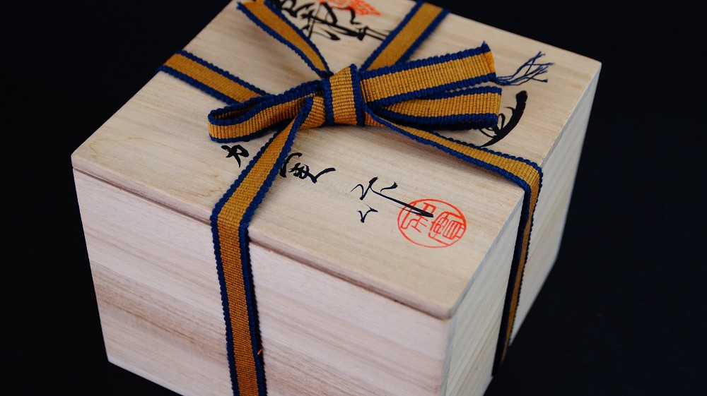 Closed storage box of the chawan made of Seto ware by Takamichi Kato with ink inscription and red artist's seal, tied with a yellow-and-blue cord