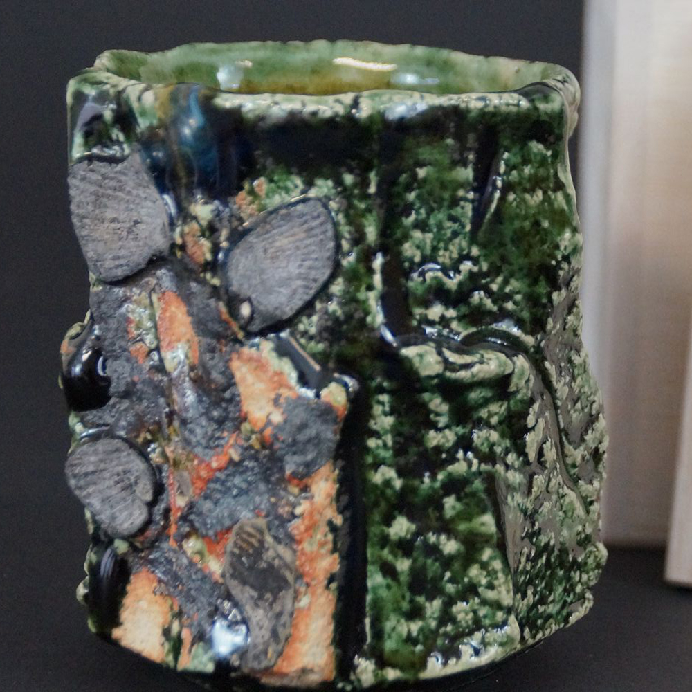 Yunomi tea bowl made of Oribe ware by Kawachi Hidetoshi in full view with stone-like glaze inclusions
