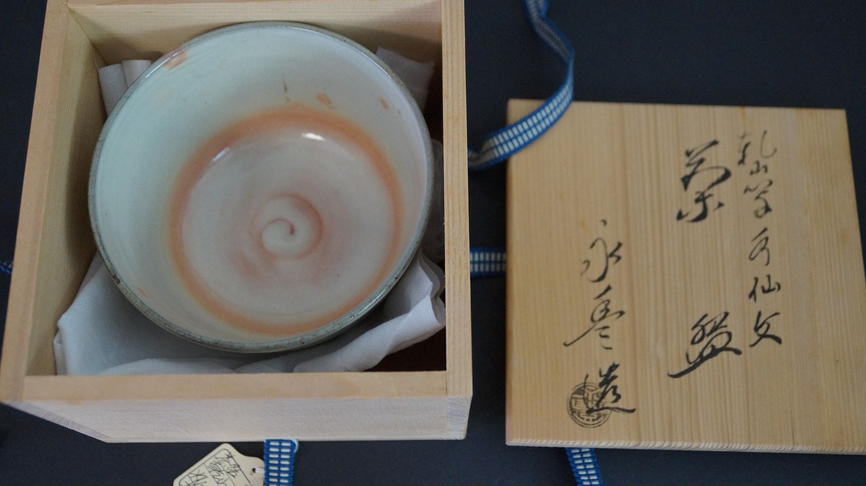 Chawan tea bowl in the opened storage box next to the inscribed box lid