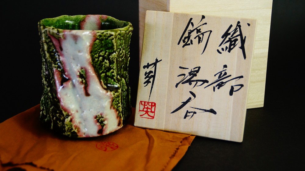 Yunomi tea bowl made of Oribe ware by Kawachi Hidetoshi front view with storage box