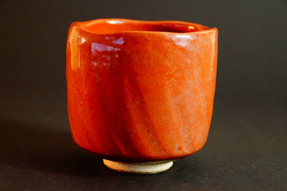 Weitere Seitenansicht des Chawan mit unregelmaessig geformtem Rand und roter Raku-Glasur von Seiraku