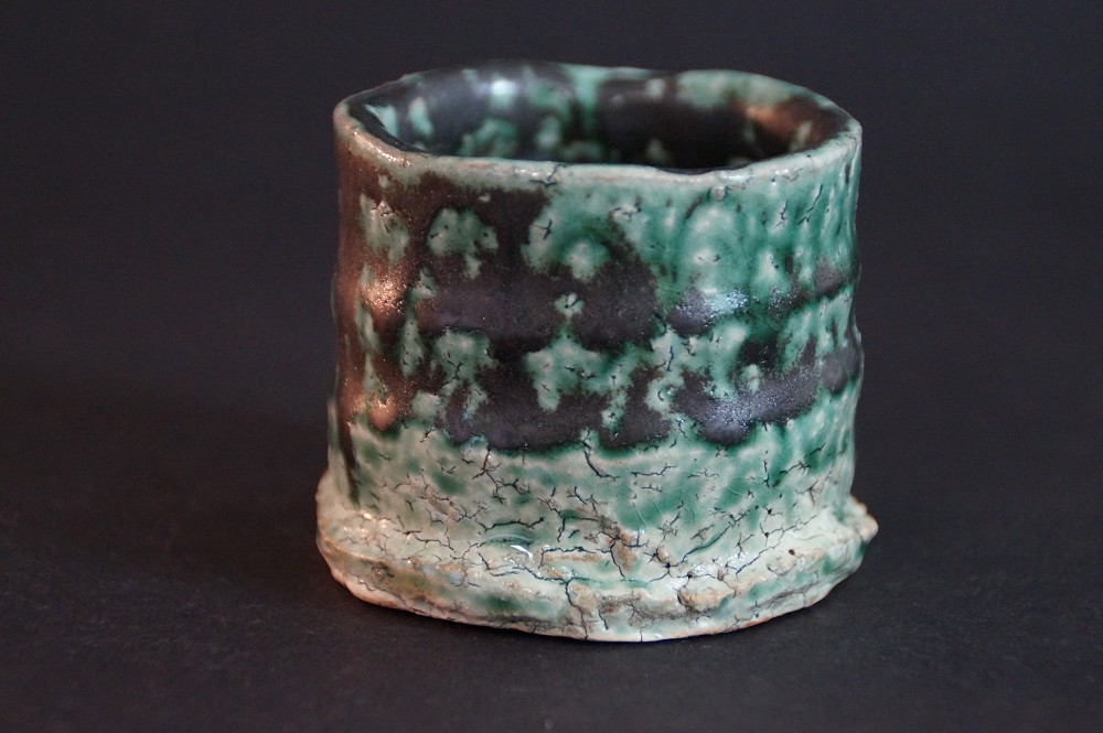Side view of the handcrafted sake bowl with green-black mottled glaze