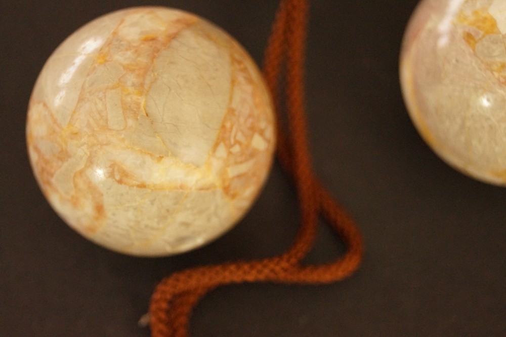 Two beige marbled stone spheres with reddish-brown veining stone close-up 3