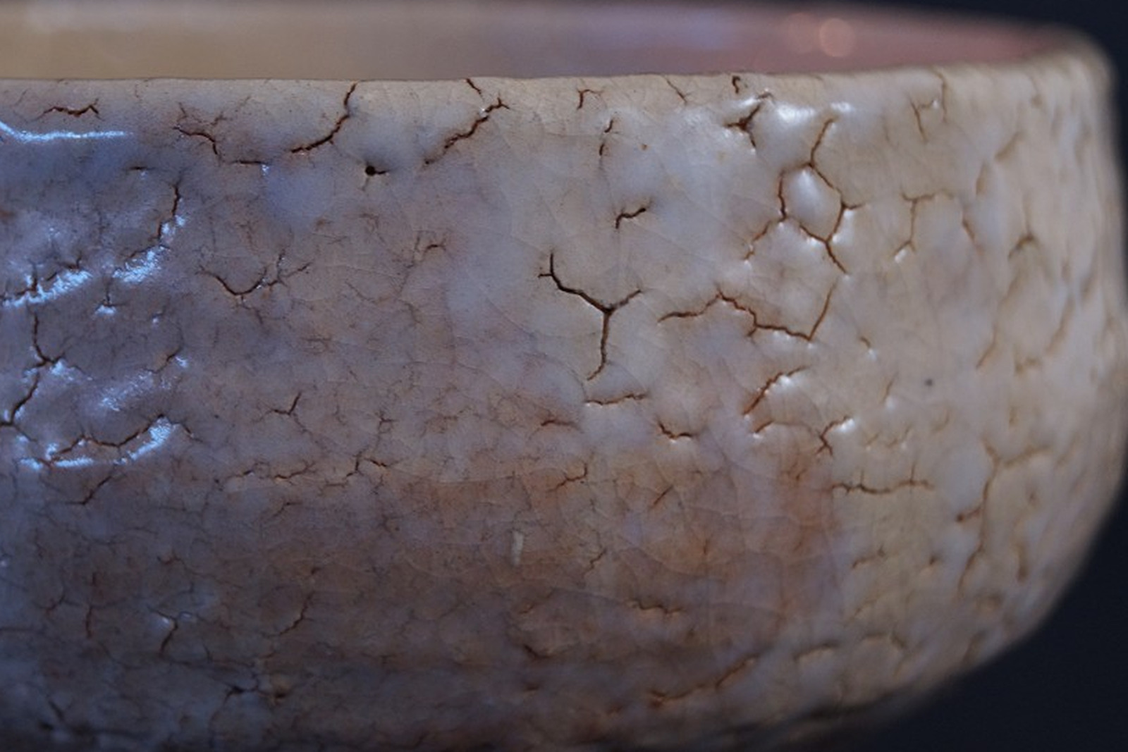 Close-up of the crackled glaze on a Japanese Hagi tea bowl with a fine, brownish-stained network of cracks