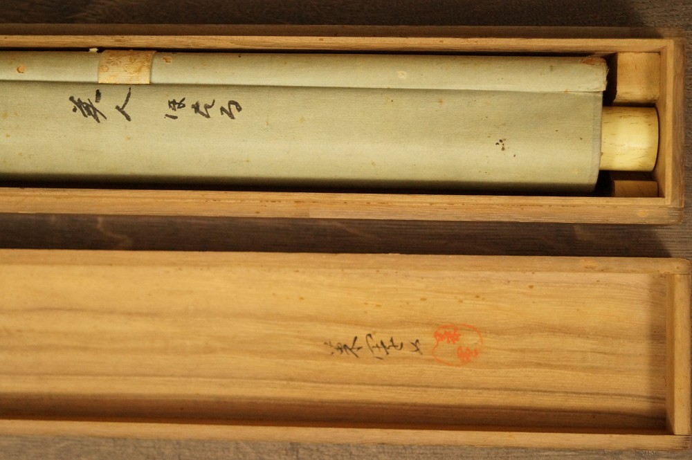 Rolled-up hanging scroll in open wooden box with ink inscription kakemono rolled up