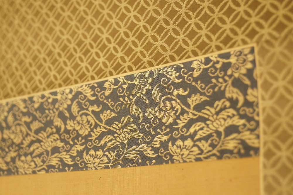 Blaugraue Brokatmontierung mit goldenem Rautenmuster Montierungsdetail
