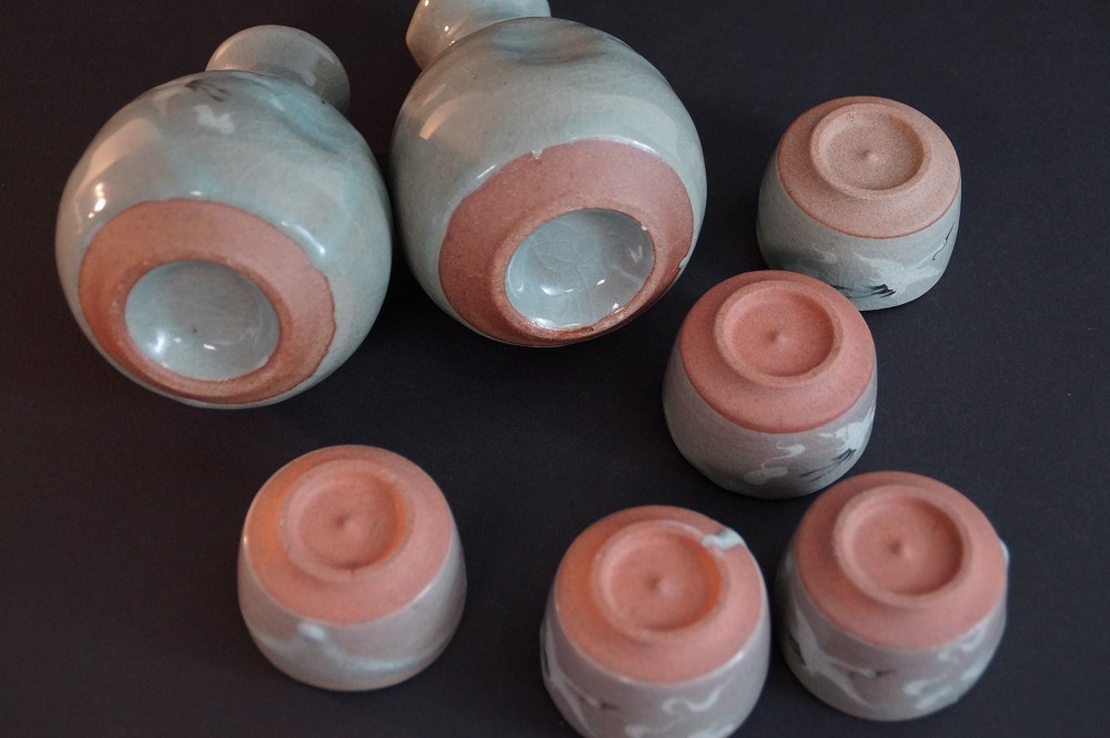 Close-up of the footrings of all seven pieces with reddish-brown unglazed clay body