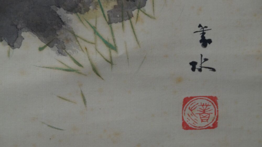 Detail view of the artist's signature and the red seal next to grass and rock in the kakemono Spring at the Old Cherry Blossom