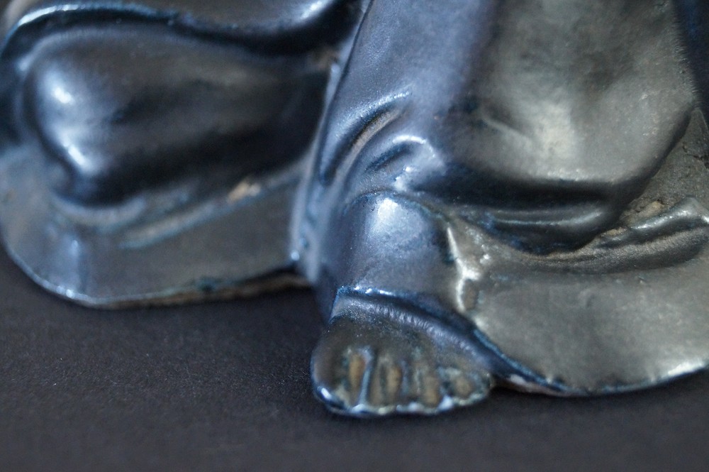 Bodhidharma Daruma Figur aus schwarzem Porzellan Fuss Nahaufnahme