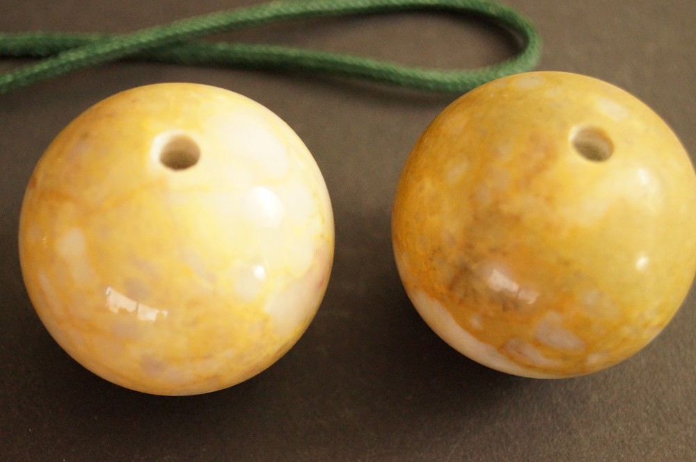 Two yellow marbled stone spheres with drill holes side by side stone close-up 4