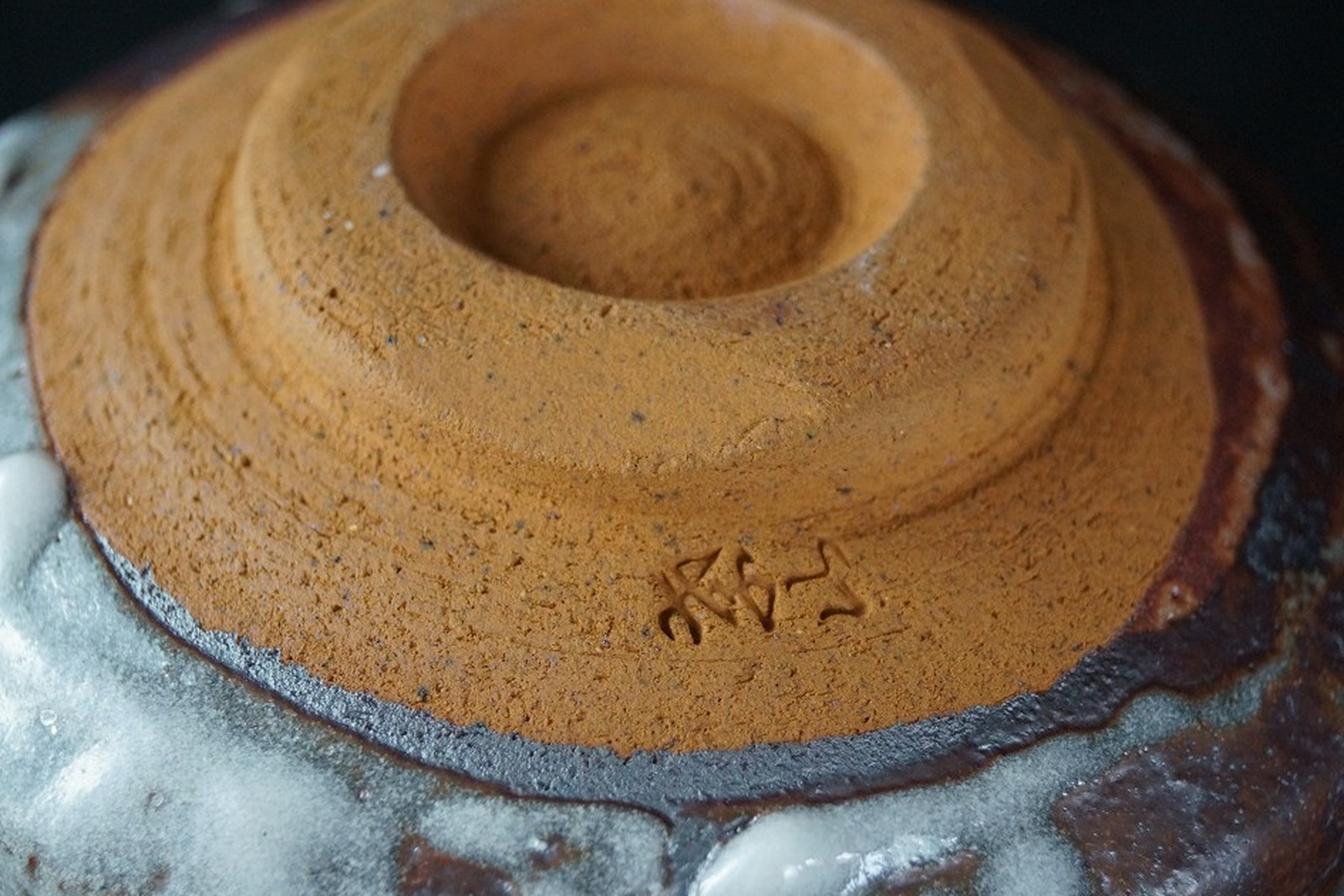 Unglazed foot ring of a Japanese Shino ware tea bowl with concentric throwing rings, tool marks, and an incised mark