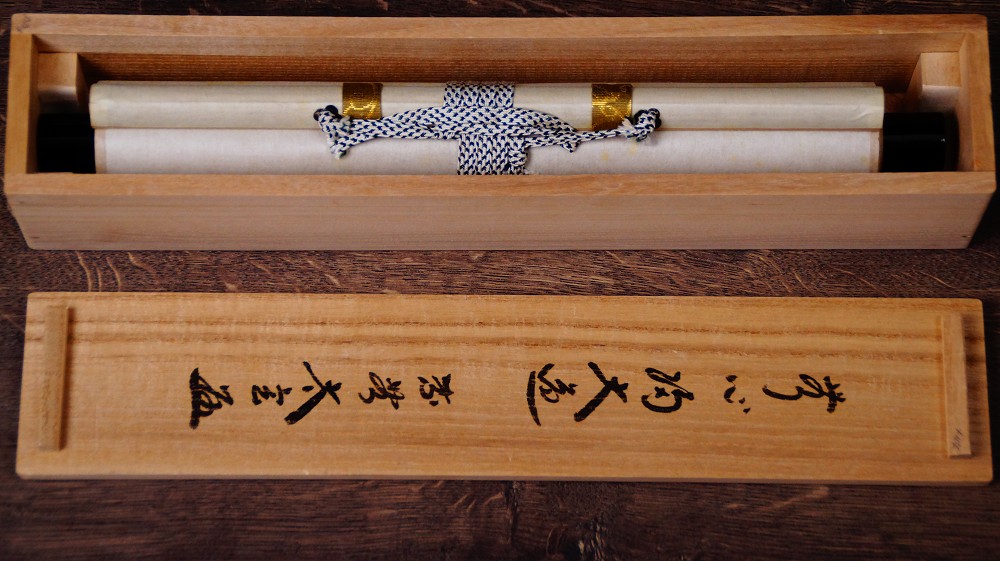 Zusammengerolltes Kakemono in der geoeffneten Aufbewahrungsbox mit Tuschebeschriftung des Deckels der Kalligrafie Ohne Gedanken zum grossen Weg