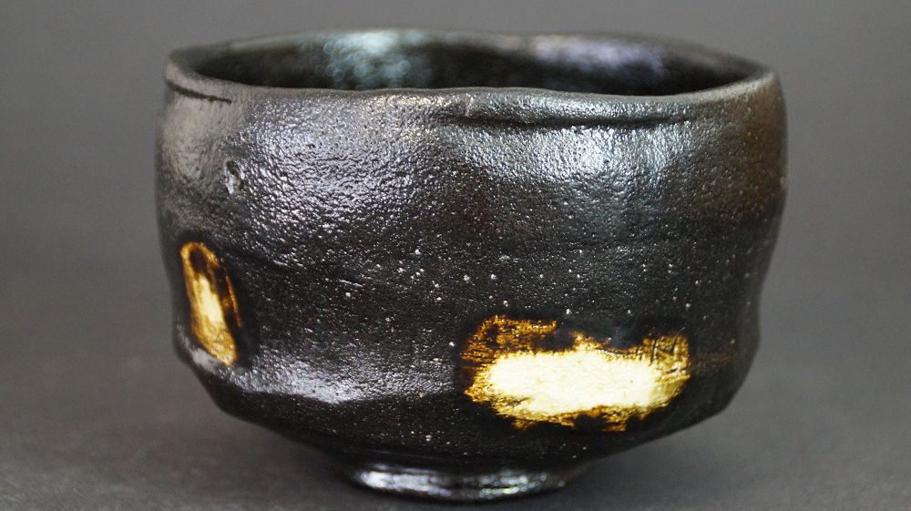 Further view of the chawan made of Raku ware with black glaze and two gold-colored glaze spots