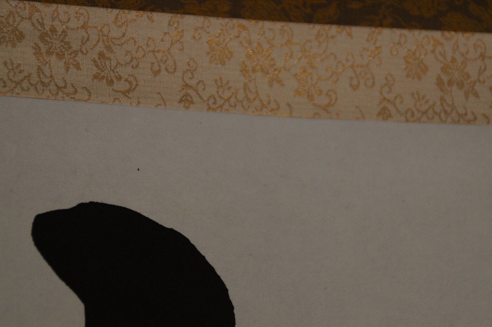Close-up of the gold-colored patterned border of the hanging scroll