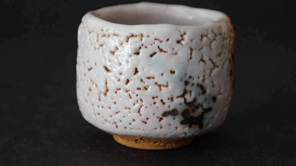 Further side view of the guinomi made of Shino ware by Takeshi Kato with orange fire marks