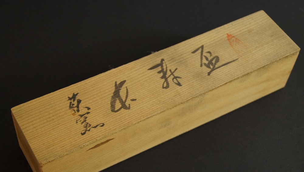 Closed elongated wooden box with inscription and red seal storage box close-up