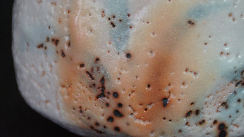 Extreme close-up of the pastel-colored glaze texture of the chawan made of Shino ware with reddish-brown speckles