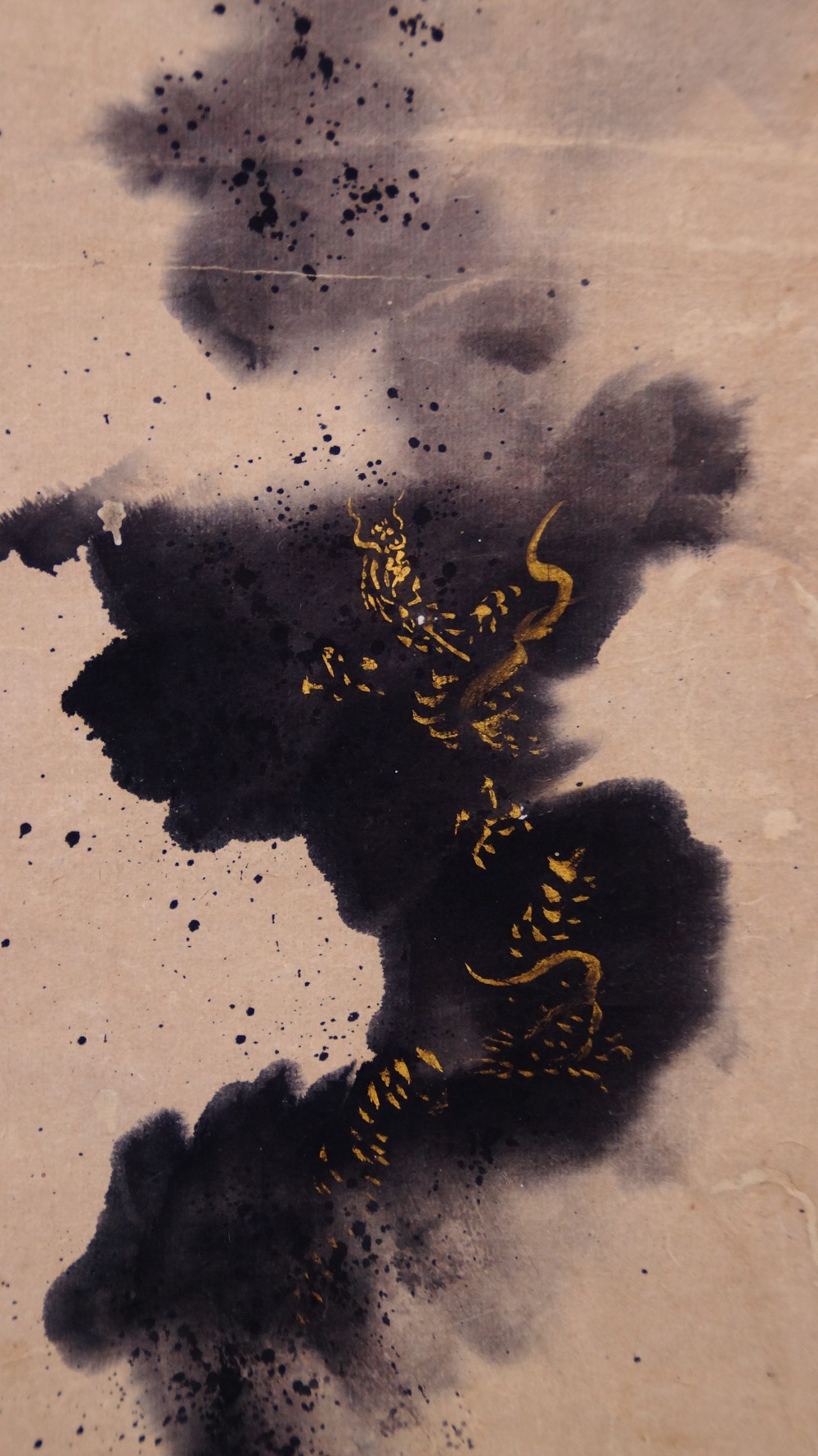 Close-up of the dragon's body painted in gold amid the ink clouds