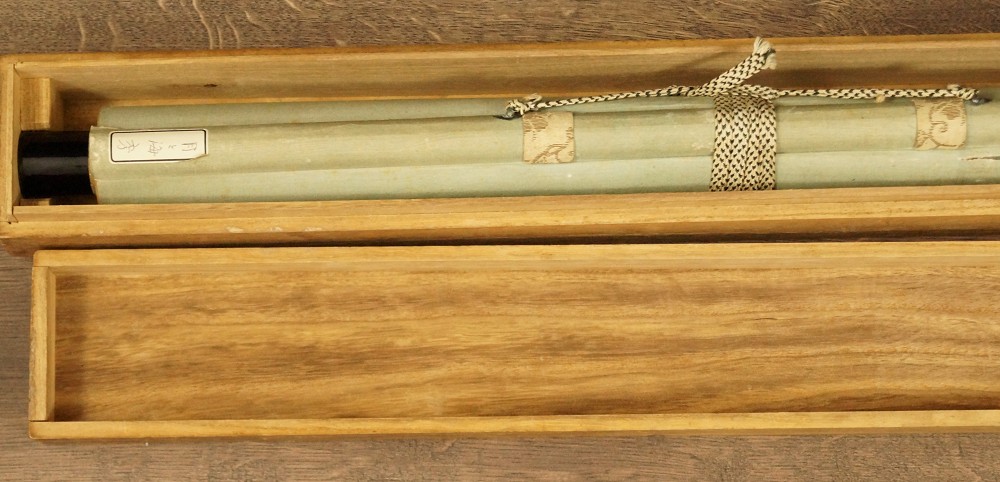 Zusammengerolltes Rollbild in geoeffneter Holzbox mit Kordel Kakemono in Aufbewahrungsbox