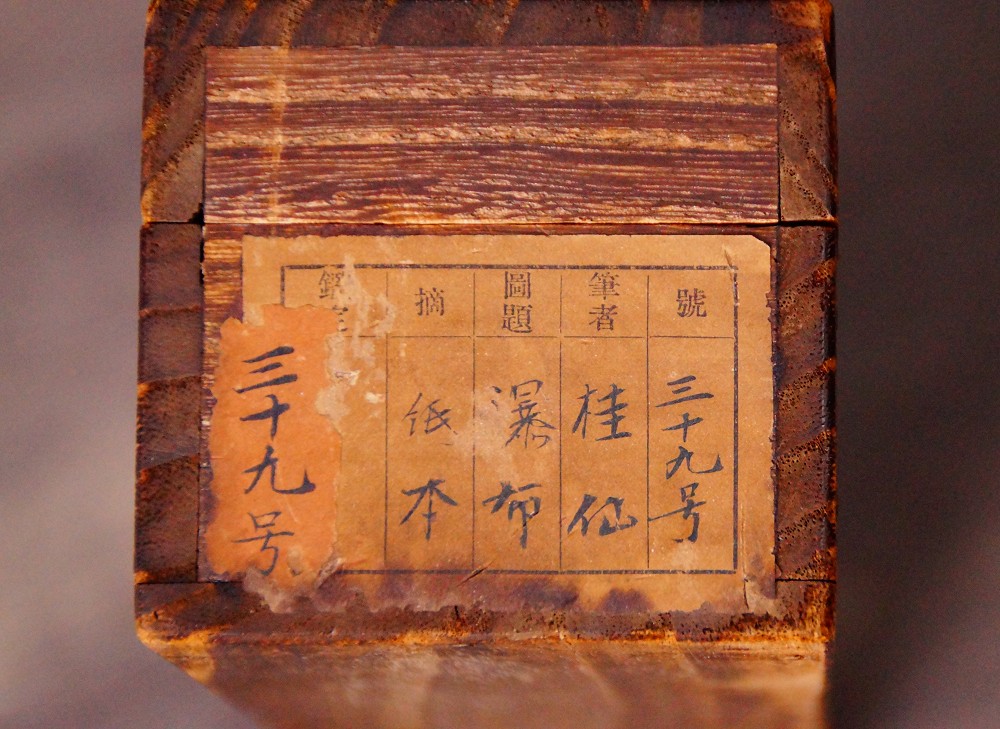 Nahaufnahme des Sammlungsetiketts auf der Stirnseite der Aufbewahrungsbox mit Titel Bakufu und Kuenstlername Keisen