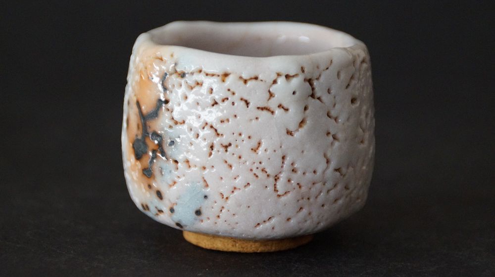 Another side view of the guinomi made of Shino ware by Takeshi Kato with dark iron spots on crackled glaze