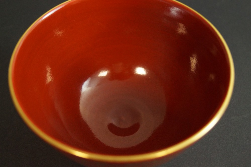 View from above into the red-glazed tea bowl with gold rim interior view close-up 2