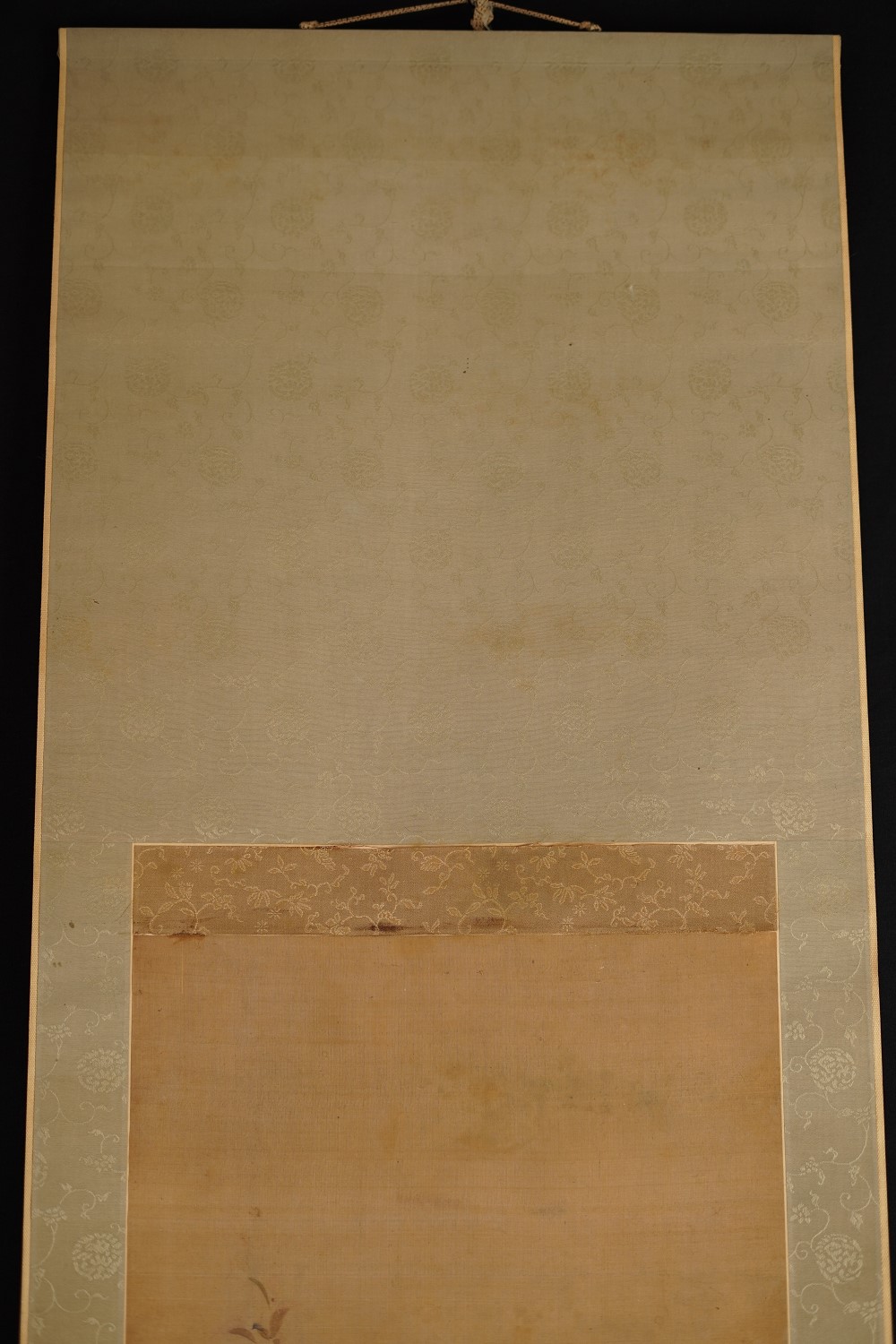 Detail view of the cream-colored silk mounting with blossom pattern and brown border of the hanging scroll Songbird on Blossoming Cherry Branch