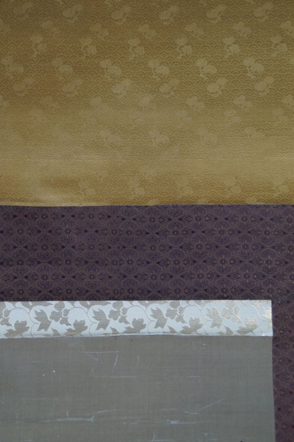Detail view of the golden and purple silk mounting with cream-colored image border of the Kakemono Heron in Quiet Peony Splendor