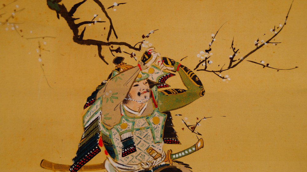 Close-up of the samurai warrior in full armor with raised arm beneath the plum branch