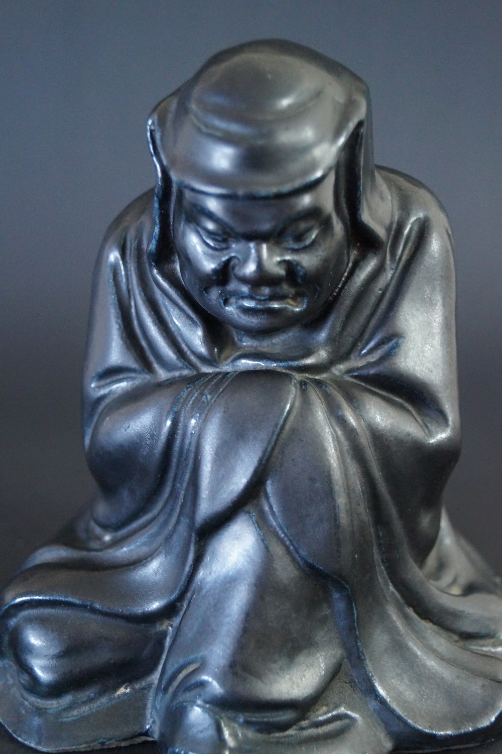 Bodhidharma Daruma Figur aus schwarzem Porzellan Frontalansicht Nahaufnahme