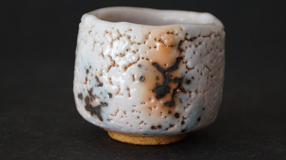 Side view of the guinomi made of Shino ware by Takeshi Kato with crackled glaze and dark iron spots