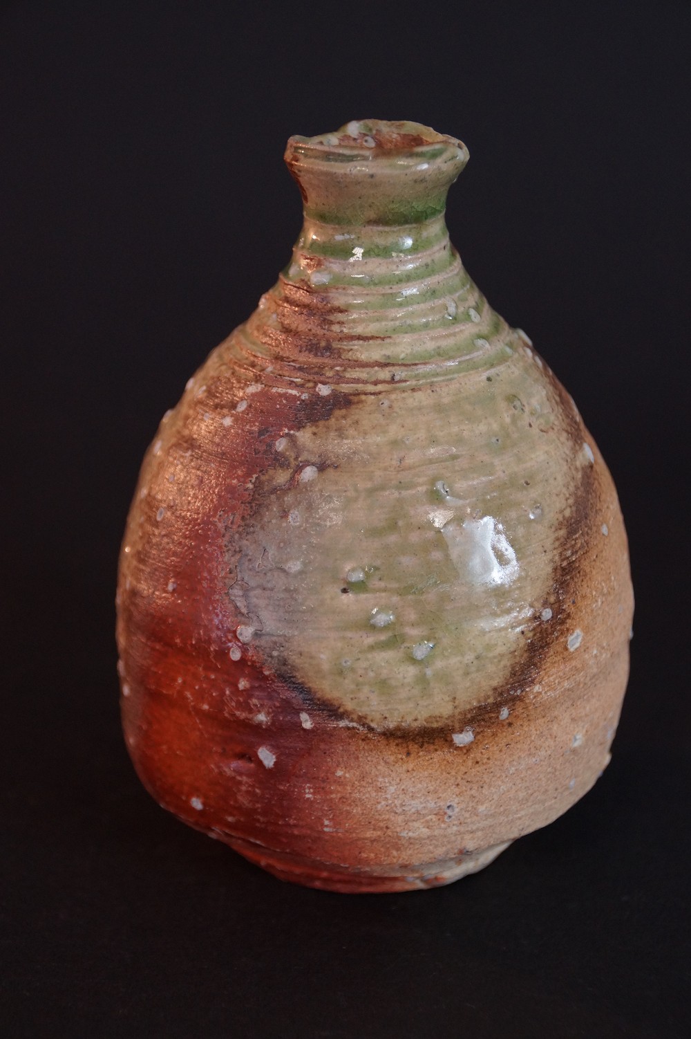 Side view of the tokkuri with iridescent green-rust-red ash-fall glaze and slightly chipped mouth rim