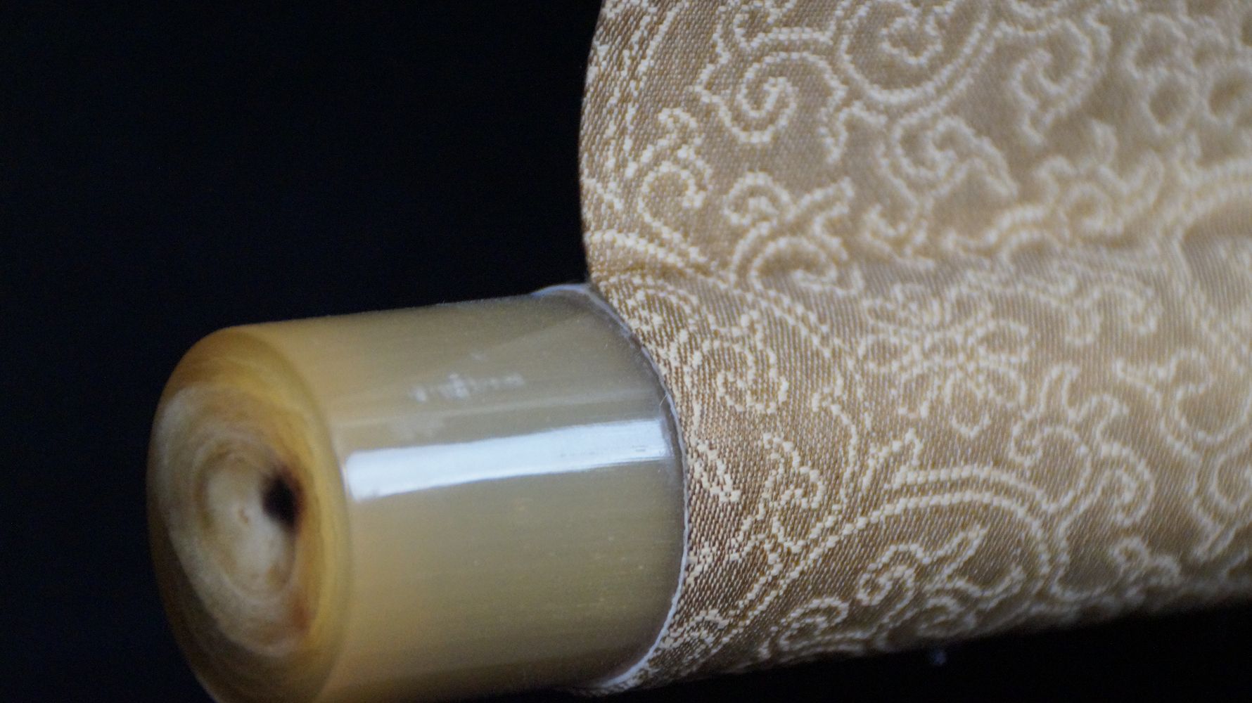 Detail view of the gold-colored brocade mounting and the ivory-colored scroll end of the kakemono Nightingale on Blossoming Plum Branch