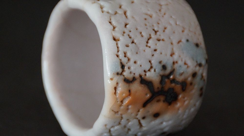 Further close-up of the irregular rim with crackled glaze and iron spots of the guinomi made of Shino ware by Takeshi Kato
