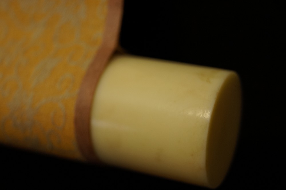 Ivory-colored scroll end with brocade fabric scroll detail