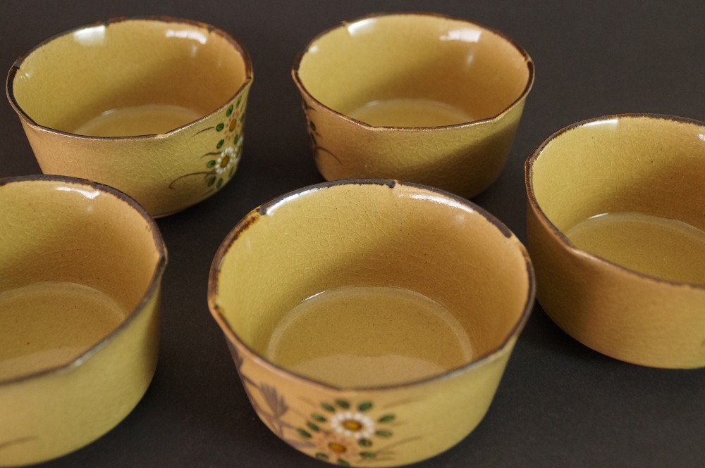 Further close-up of the five bowls with visible dark brown glazed interior