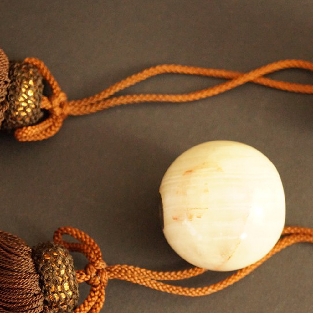 Two light-colored natural stone spheres with brown silk tassels Set Close-Up Preview