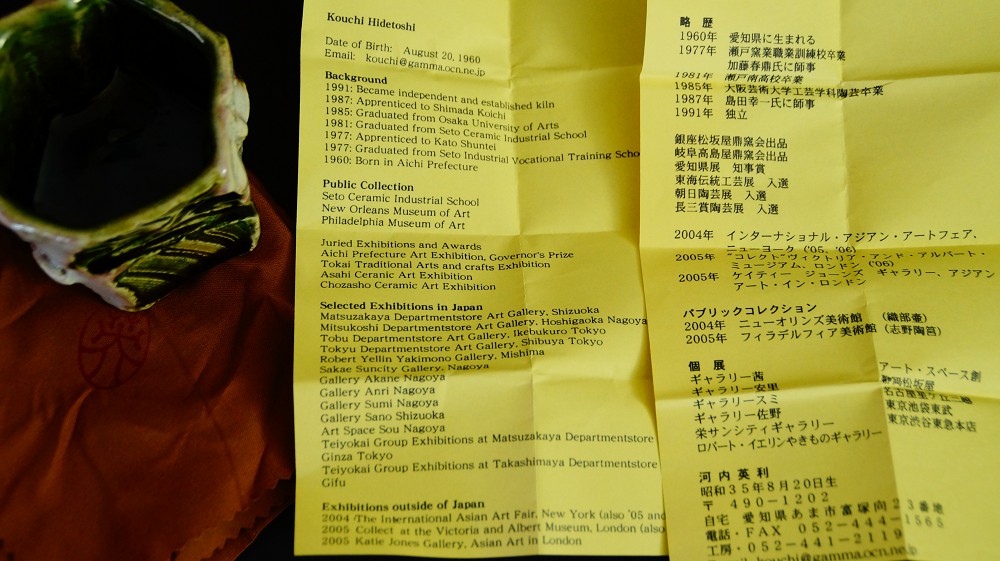 Biography sheet of the ceramic artist Kouchi Hidetoshi next to the guinomi
