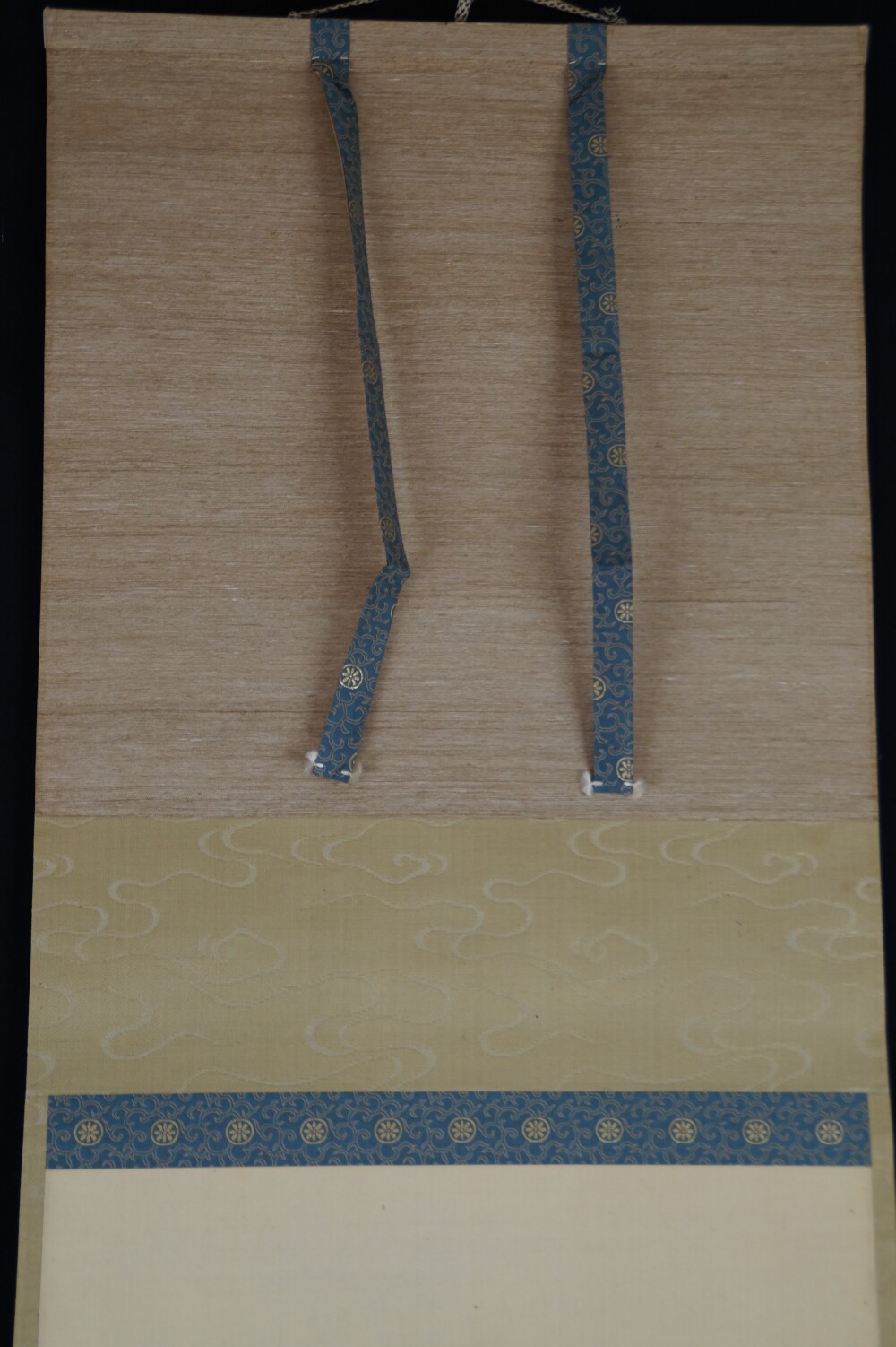Detail view of the greenish cloud mounting with blue binding cords on the hanging scroll Encounter at the Edge of the Waterfall by Yagioka Shunzan