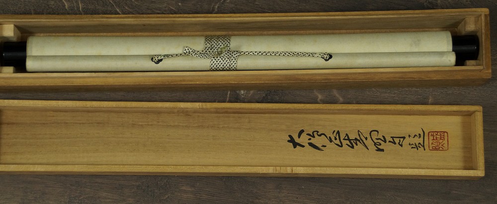 Rolled-up hanging scroll in the labeled storage box with cord