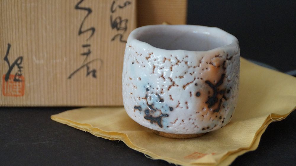 Guinomi made of Shino ware by Takeshi Kato with the matching inscribed storage box in the background